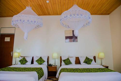 two beds in a room with white walls and wooden ceilings at One Click Hotel in Kigali