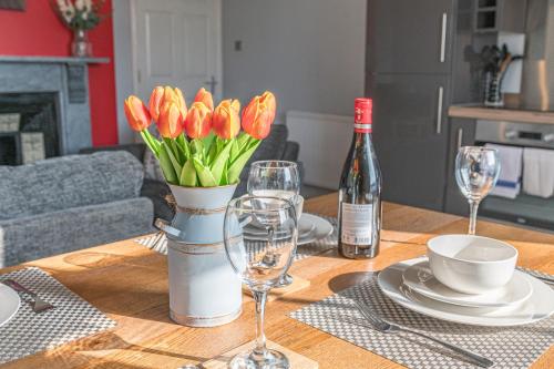 a table with a vase of flowers and wine glasses at The Apartments Coniston in Coniston