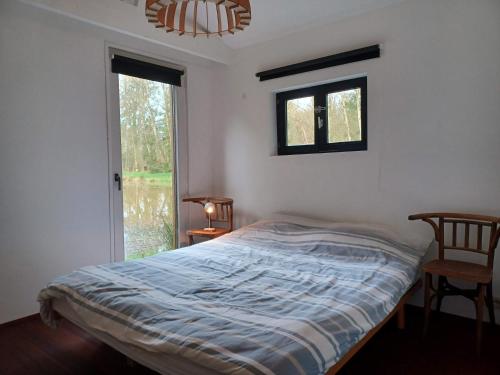 a bedroom with a bed and a window and a lamp at De Vijver in Geel