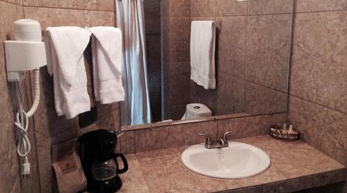a bathroom with a sink and a mirror and towels at Ramada by Wyndham Tikal Isla de Flores in Flores