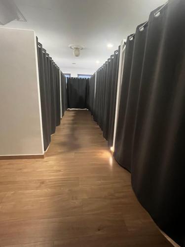 un corridoio fiancheggiato da tende nere in una stanza di Albergue Melide a Melide