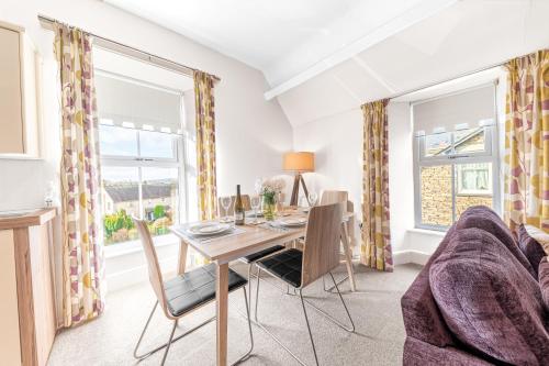 a dining room with a table and chairs and a couch at The Apartments Coniston in Coniston