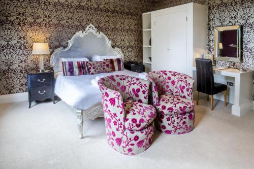 a bedroom with a bed and two chairs at The Kings Head Country Hotel in Great Bircham