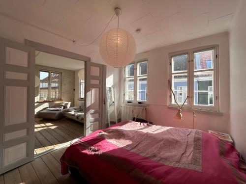 a bedroom with a bed in a room with windows at Bylejlighed i det gamle Svendborg in Svendborg