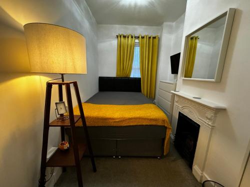 a small bedroom with a bed and a lamp at Galaxy apartments Brentwood in Brentwood