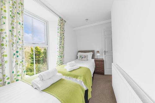 a white bedroom with two beds and a window at The Apartments Coniston in Coniston