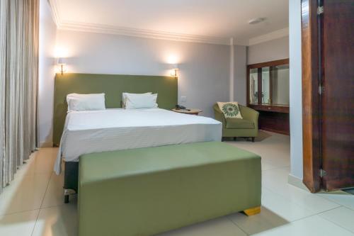 a bedroom with a large bed and a chair at Umuarama Plaza Hotel by Castelo Itaipava in Goiânia