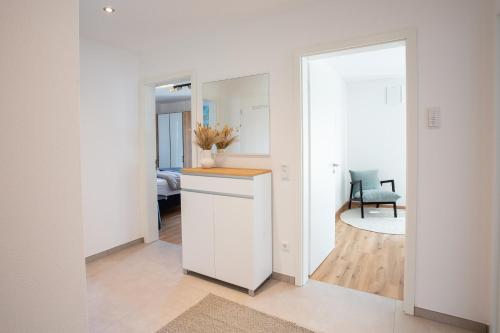 a white kitchen with a counter and a mirror at Siebenschläfer Appartements in Eging am See