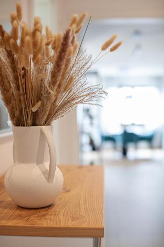 a white vase filled with dried plants on a table at Siebenschläfer Appartements in Eging am See