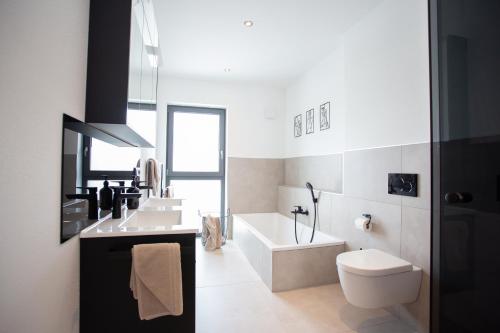 a bathroom with a sink and a toilet and a tub at Siebenschläfer Appartements in Eging am See