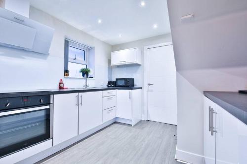 een witte keuken met witte kasten en zwarte apparaten bij StayRight Whitchurch Place: 2-bed Flat in Cardiff in Cardiff