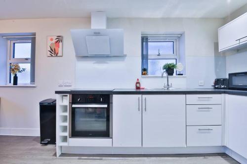 een keuken met witte kasten en een zwart apparaat bij StayRight Whitchurch Place: 2-bed Flat in Cardiff in Cardiff
