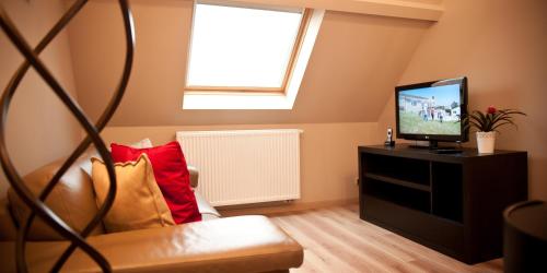 a living room with a couch and a television at B&B Innbrugas in Bruges