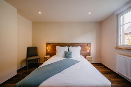 a bedroom with a large bed and a chair at Résidence Les Charmes in Boofzheim