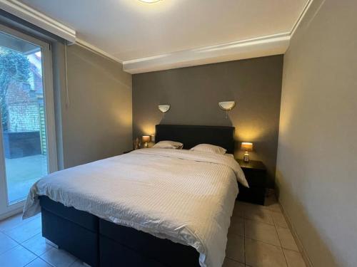 a bedroom with a large bed and a window at Gezellig centraal gelegen app voor 3 personen in Koksijde