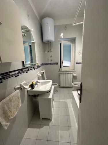 Baño blanco con lavabo y aseo en Solymar House Lacco Ameno, en Isquia