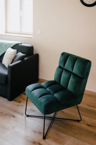 a green chair in a living room with a couch at Résidence Les Charmes in Boofzheim