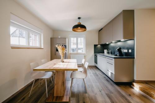 a kitchen with a wooden table and white chairs at Résidence Les Charmes in Boofzheim