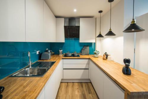 a kitchen with white cabinets and a wooden counter top at BethnalGreen Apartments by Sleepy in London