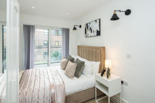 a white bedroom with a bed and a window at BethnalGreen Apartments by Sleepy in London