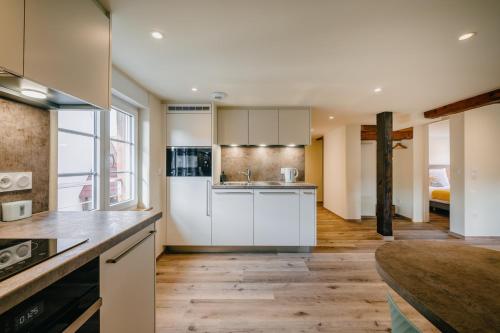 a kitchen with white cabinets and a wooden floor at Résidence Les Charmes in Boofzheim