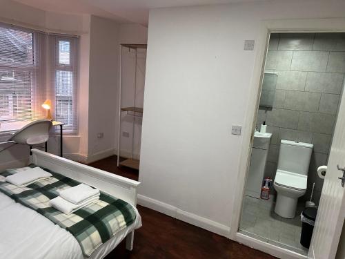 a bedroom with a bed and a toilet and a mirror at Stratford Guesthouse in London