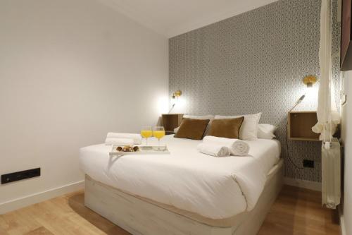 ein Schlafzimmer mit einem großen weißen Bett mit zwei Gläsern Wein in der Unterkunft Madrid Río Suites in Madrid