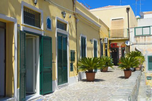 a street with green shutters and potted plants at Sabrina Suite in Milazzo