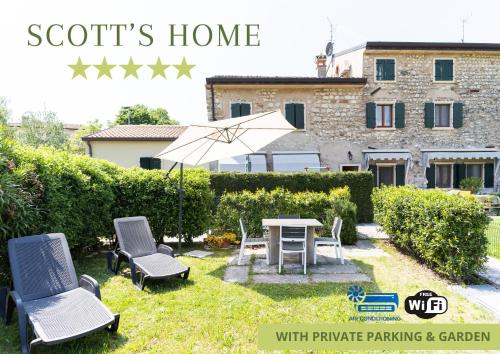 un jardín con mesa, sillas y sombrilla en Garda Lake & Relax - Cottage On The Hill, en Caprino Veronese