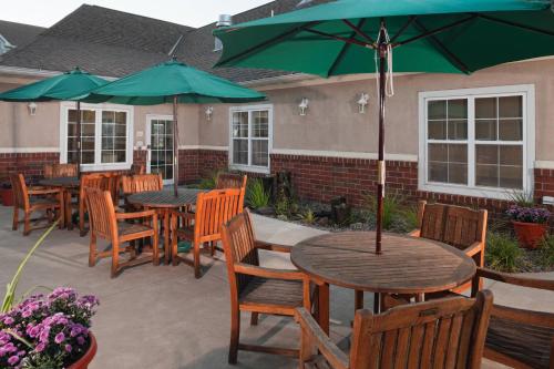 un patio con tavoli, sedie e ombrelloni verdi di Residence Inn by Marriott Bloomington by Mall of America a Bloomington