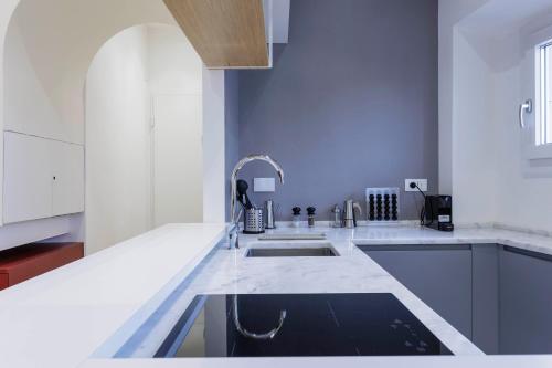 uma cozinha com balcões brancos e um lavatório em Duomo View Apartment em Florença