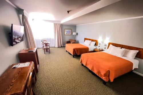 a hotel room with two beds and a television at Hotel Diego de Almagro Concepción in Concepción