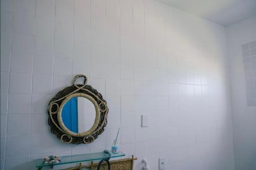 a bathroom with a mirror on a white tiled wall at Casa Prema - Experiência vegana e terapêutica à beira-mar in Maceió