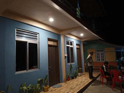 un hombre parado fuera de una casa con una pared azul en The Onish Stay Inn en Rangpo