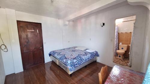 een kleine slaapkamer met een bed en een toilet bij Casa Yelitza in San Pedro La Laguna