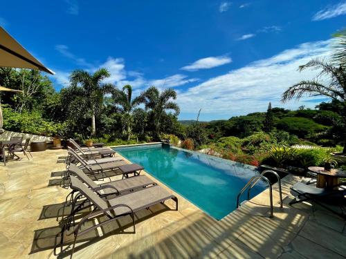 uma piscina com espreguiçadeiras num pátio em Pousada Villa Canaã em Búzios