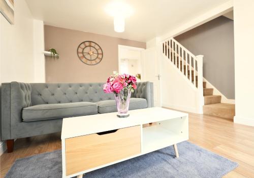 a living room with a couch and a vase of flowers on a table at Central Getaway House with Parking, Garden, Wi-Fi in Stafford
