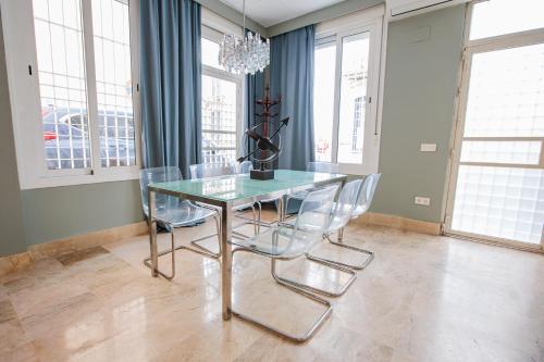 uma sala de jantar com uma mesa de vidro e cadeiras em Apartamento Arrayan em Sevilha