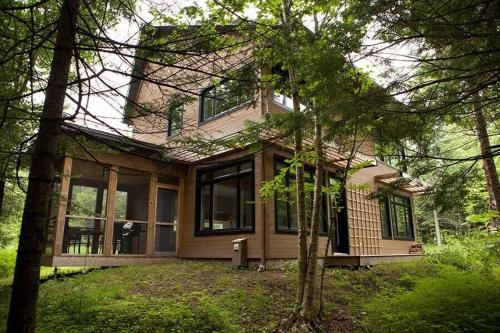 a large house with windows and trees in front of it at Cottage 61 des Cervidés in Eastman