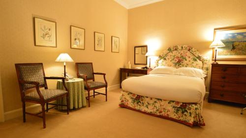 a bedroom with a bed and two chairs and a desk at Kinloch House Hotel in Blairgowrie