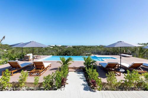 a resort with a pool and chairs and umbrellas at Onyx I Long Bay Retreat I Luxury Stay Near Grace Bay & Long Bay Beach in Long Bay Hills