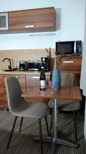 a table with two chairs and a bottle and a vase on it at Apartmány u jezera Fami*** in Doksy