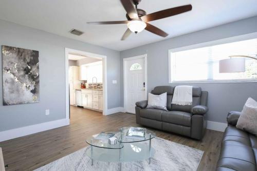 Una sala de estar con un sofá y un ventilador de techo. en Serenity Retreat PoolSpa BBQ WorkSpace WiFi 3Bdrm, en Palm Beach Gardens