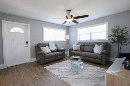 Una sala de estar con dos sofás y un ventilador de techo. en Serenity Retreat PoolSpa BBQ WorkSpace WiFi 3Bdrm, en Palm Beach Gardens