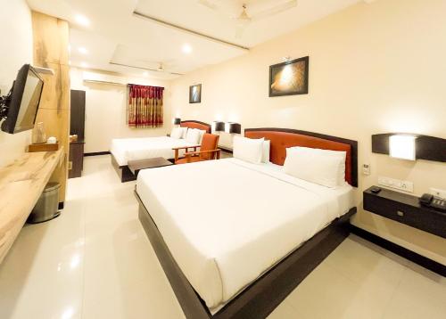 a hotel room with two beds and a television at Shree Residency in Erode