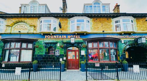 a brick building with a red door on a street at Fountain Hotel in London