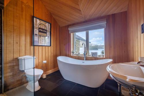 a bathroom with a tub and a toilet and a sink at Lilymere Boat House in Sedbergh