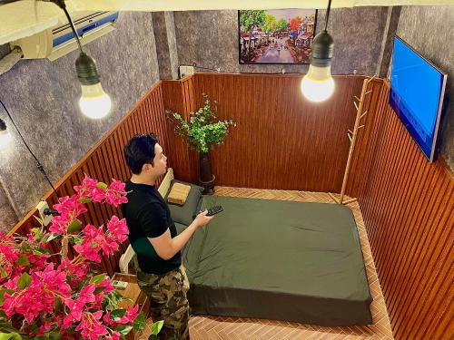 a man holding a cell phone in a room with flowers at Old Building 1939 in Hanoi