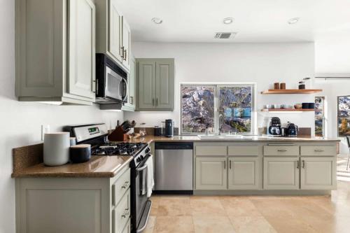 a kitchen with white cabinets and a stove top oven at Boulder Surrounded Escape- ANOTHERdeserthouse in Yucca Valley