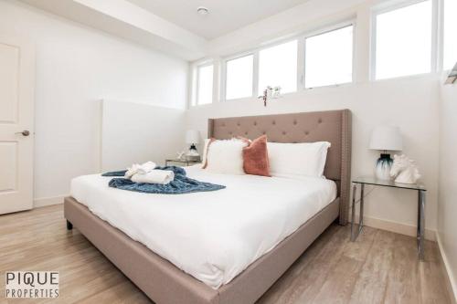 1 dormitorio con 1 cama grande con sábanas y almohadas blancas en Spacious Modern Suite - King Bed - Central - WiFi! en Edmonton